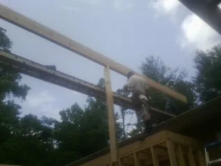Carpenter setting a ridge beam over a new addition frame — Ice Dam Removal by Roofing Brothers in Southborough