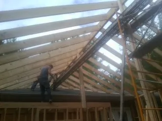 Rafters going up over a new addition with a worker on the wall in Southborough