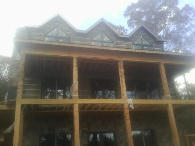 Dormers and porch framing on a large log home under construction — Roof Coating work by our crew in Southborough