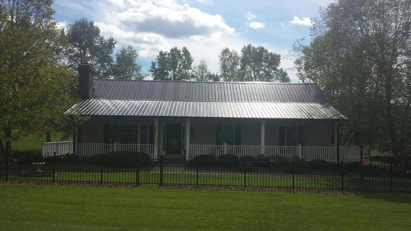 Gray metal roof on a brick ranch with a full width front porch — Gutter Guard Installation work by our crew in Southborough