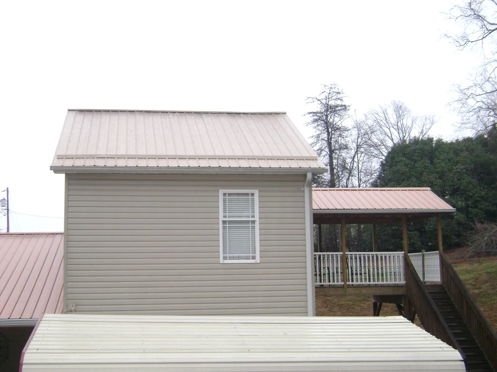 Tan metal roofs on a two story addition and attached porch, from a Roof Replacement job in Southborough