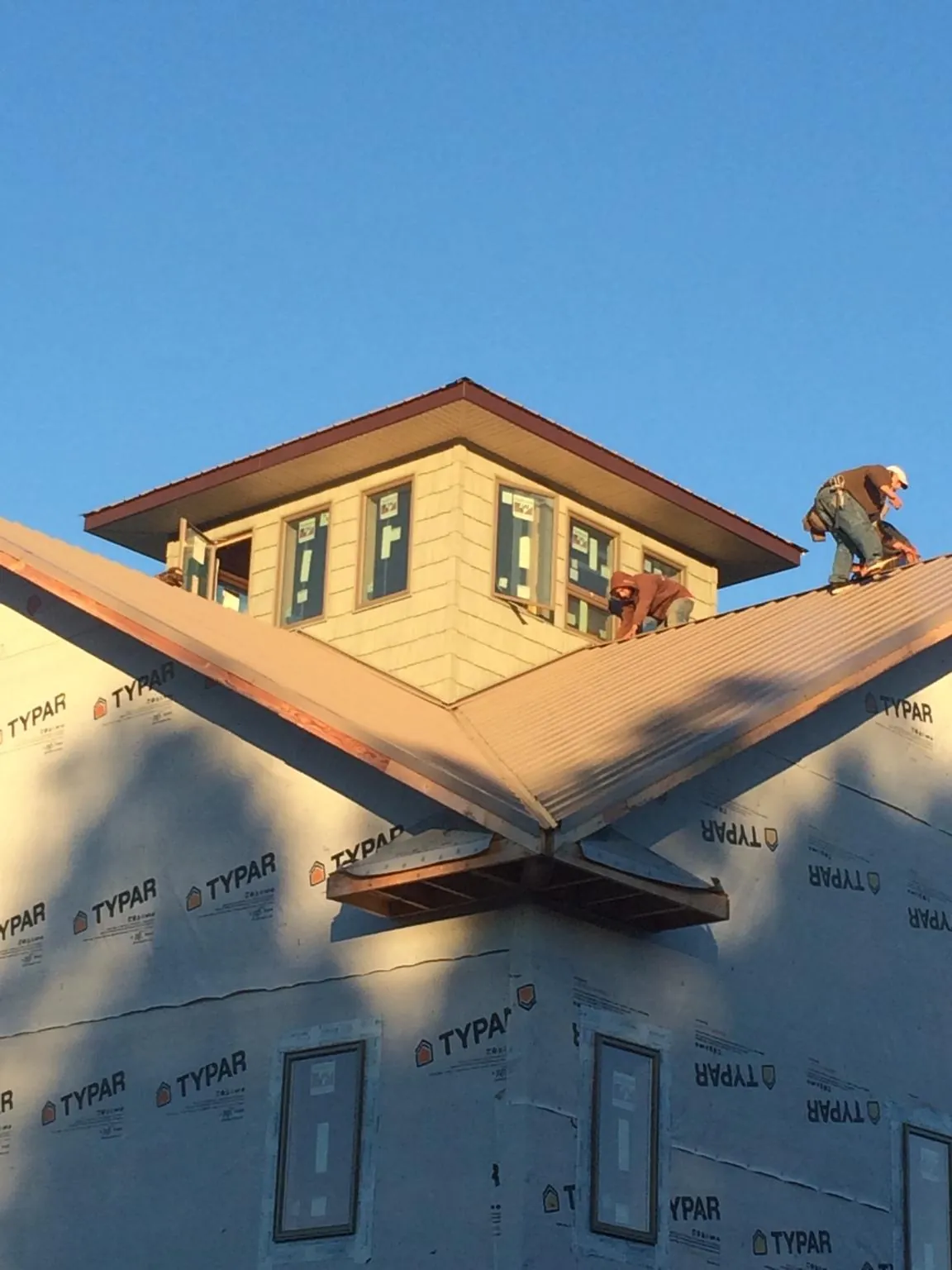 Roofers working around a rooftop cupola on a new metal roof at sunset — Roof Waterproofing in Southborough by Roofing Brothers